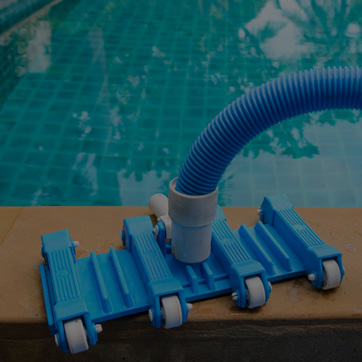 A photograph of an automated pool cleaner by the side of a swimming pool