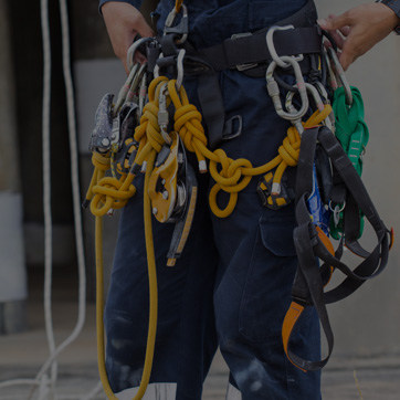 A photograph of a person wearing a harness with ropes